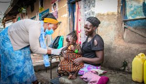 Staff Community Nurse Frida works with a Ugandan family to provide healthcare