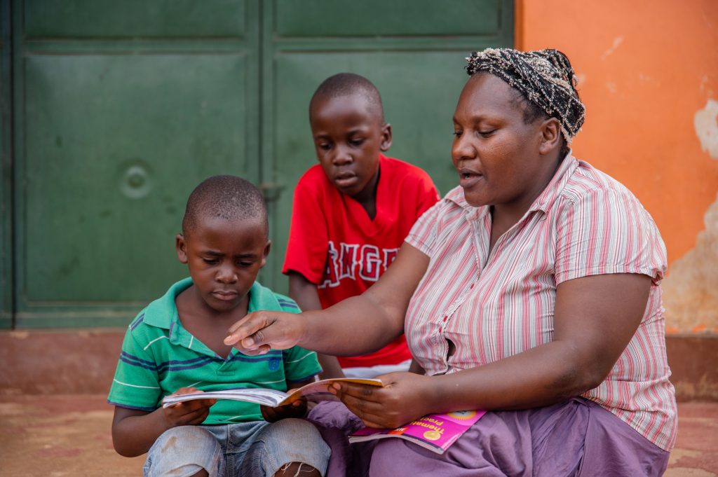 A ugandan woman and her two children sitting on a step